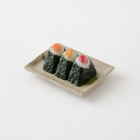 Three pieces of sushi on a rectangular plate with a white background